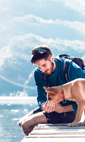 Jóven con su perro al borde del lago