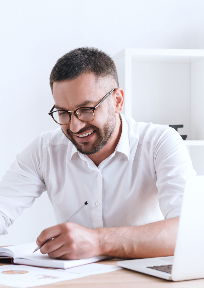 Hombre sonriendo y escribiendo en una agenda.