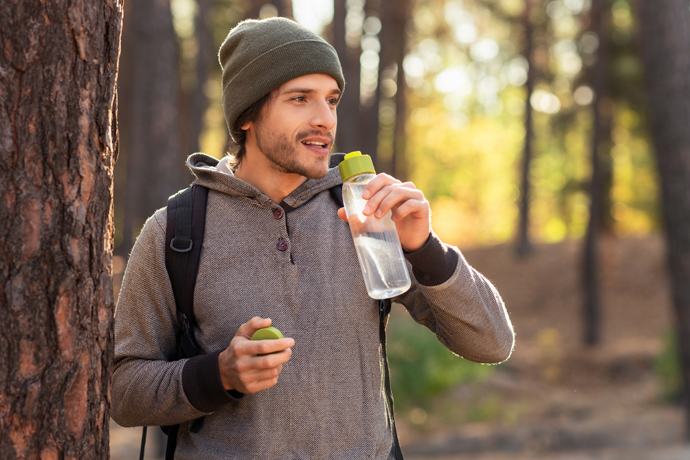 Hombre tomando agua durante una caminata