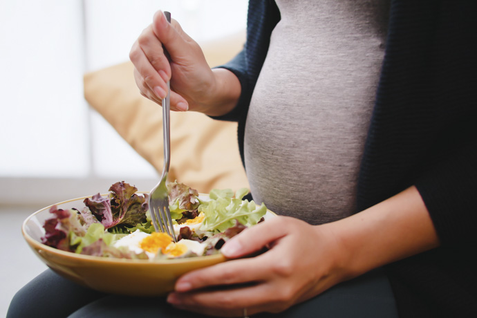 Mujer embarazada come alimentos saludables