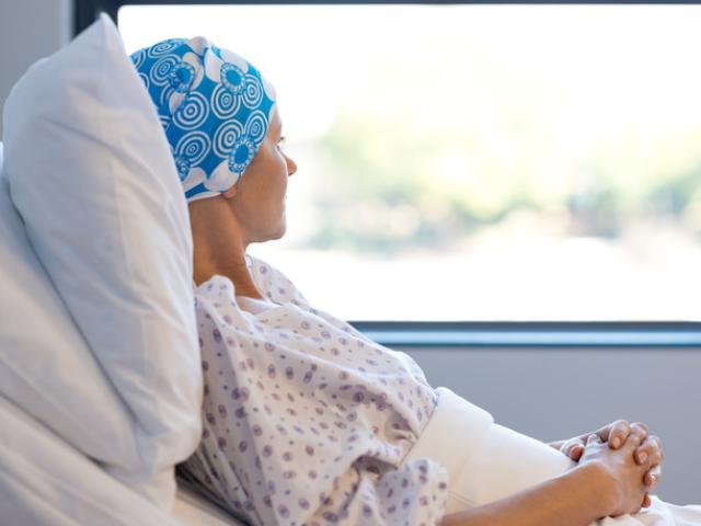 Mujer con cáncer tumbada en cama de hospital