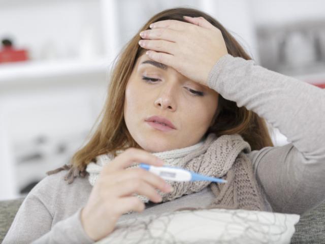 Mujer usa termómetro para saber si tiene fiebre